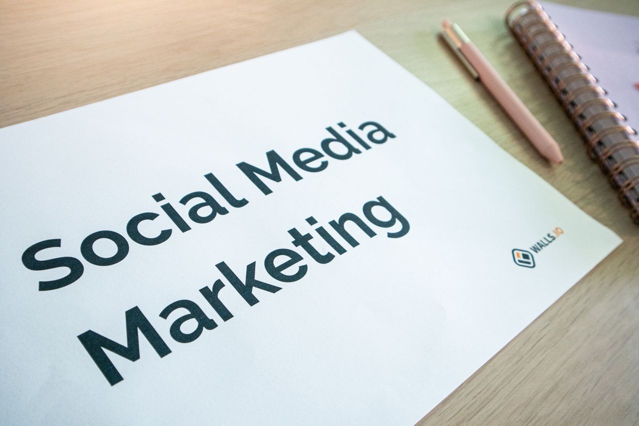 heros-img A close-up view of a social media marketing document resting on a desk beside a pen and notebook.